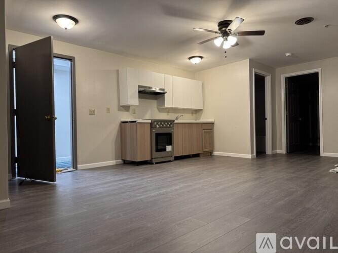 A spacious living room with a kitchenette and hardwood floors.