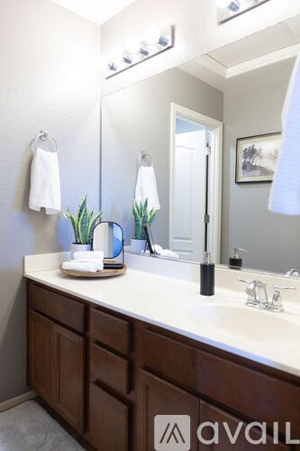 A bathroom with a white counter top and a brown cabinet.