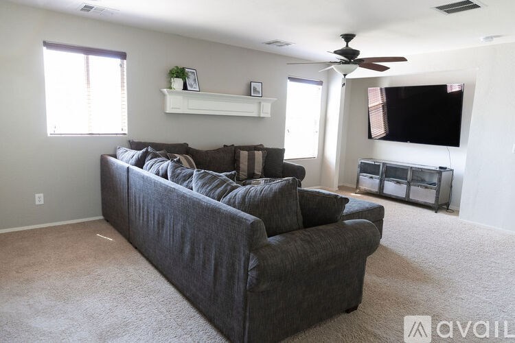 A living room with a grey couch and a flat screen TV mounted on the wall.