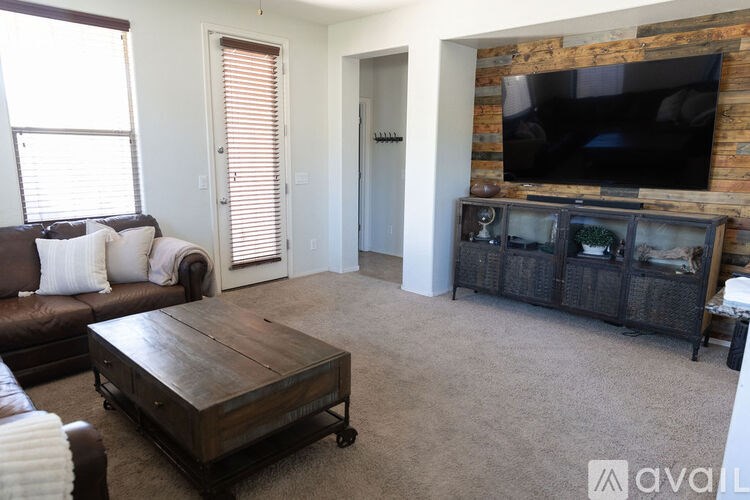 A living room with a brown couch, a wooden coffee table, and a TV mounted on a brick wall.