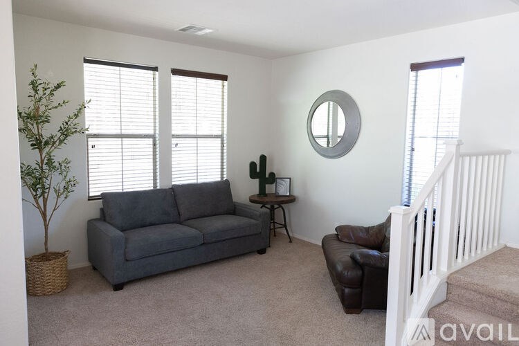A living room with a grey couch, a small table, and a mirror on the wall.