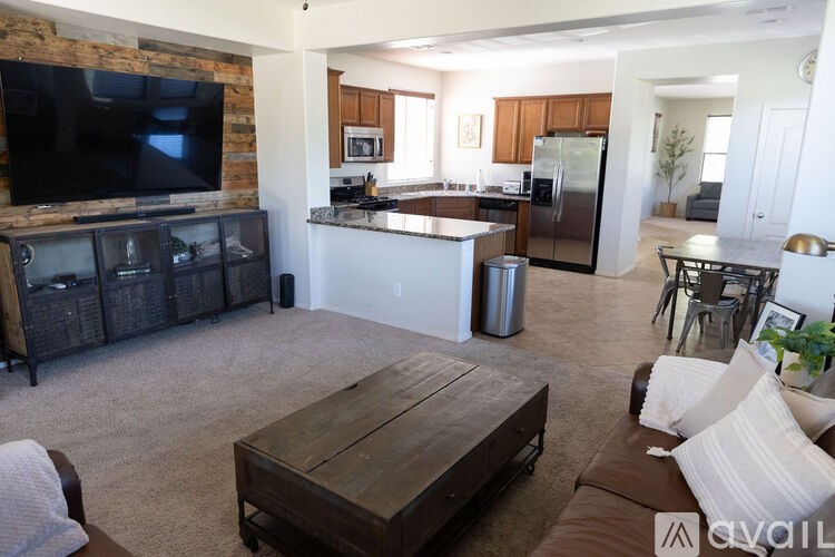 A living room with a wooden coffee table and a kitchen area in the background.