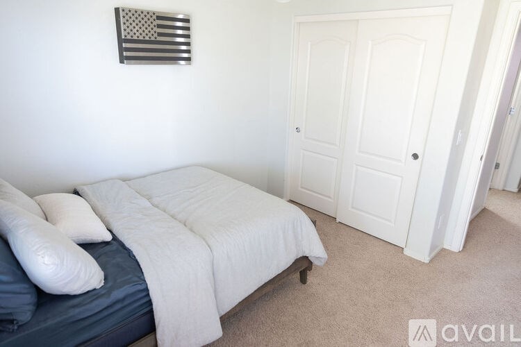 A bedroom with a bed, pillows, and a flag on the wall.