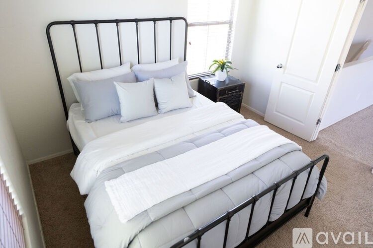 A black metal bed with white bedding and pillows in a room.
