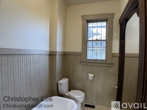 A bathroom with a toilet, sink, and window.