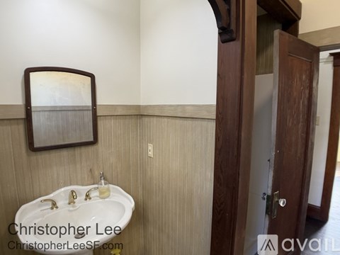 A bathroom with a sink, mirror and wooden door.