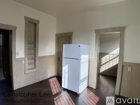 A white refrigerator in a room with wooden walls and a window.