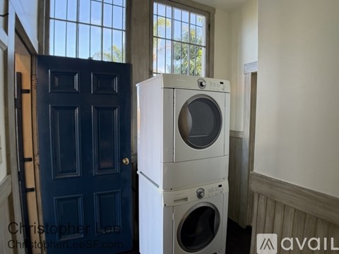A stack of white washing machines in a room with a blue door.