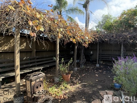 A backyard with a wooden deck and a tree with orange leaves.