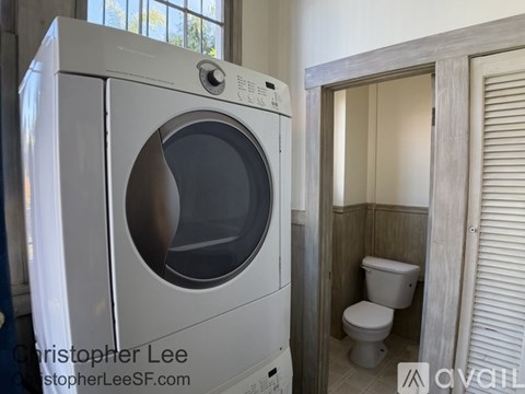 A white front loading washing machine in a small bathroom.