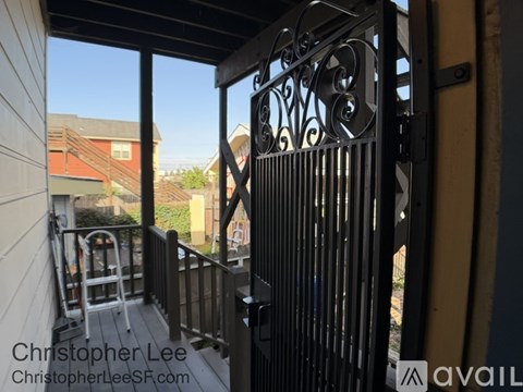 A black wrought iron gate is open to a balcony.