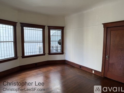 A room with wooden floors and three windows.