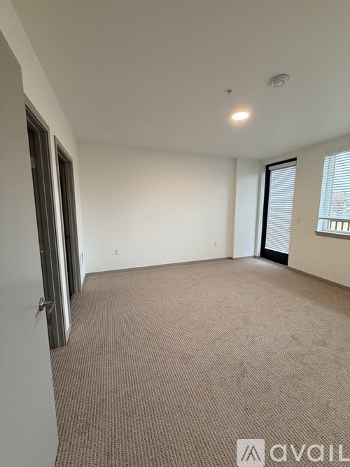 A room with carpeted floor and a window with blinds.