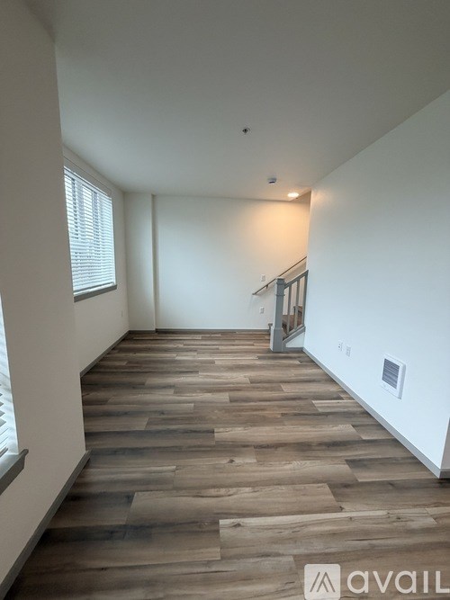 A hallway with wooden flooring and white walls.