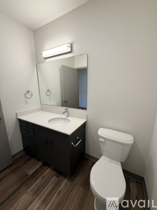 A bathroom with a toilet, sink, and mirror.