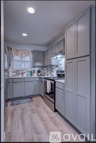 A kitchen with grey cabinets and a wooden floor.