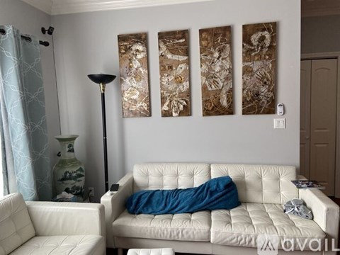 A living room with a white couch and a lamp.