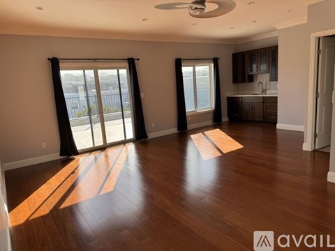 A spacious room with wooden floors and a ceiling fan.
