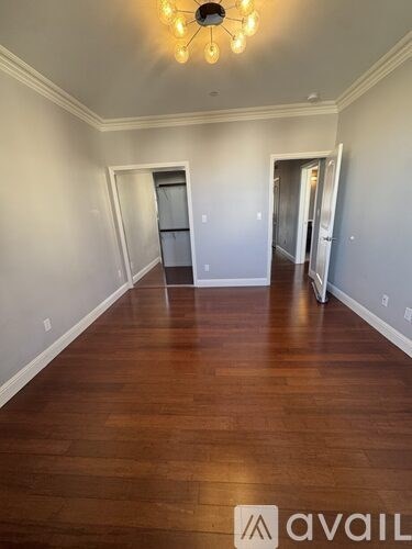 A hallway with wood floors and a chandelier.