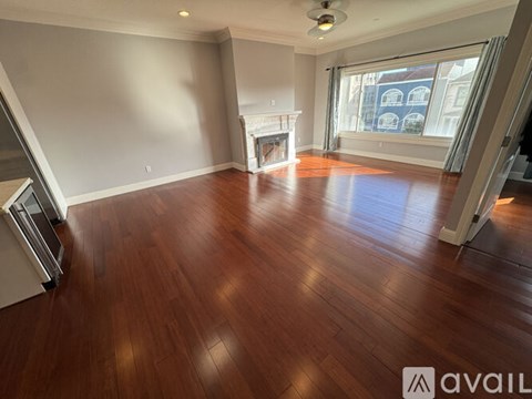 A spacious room with wooden flooring and a fireplace.