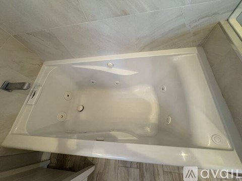 A white bathtub with a shower head and faucet.