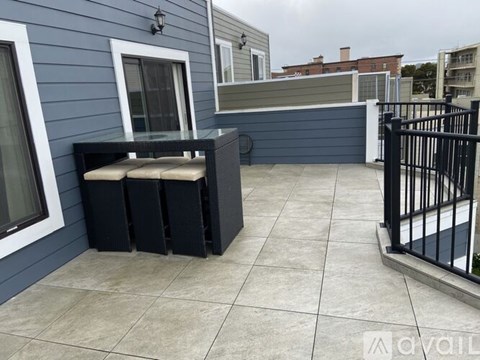 A patio with a black bench and a black railing.