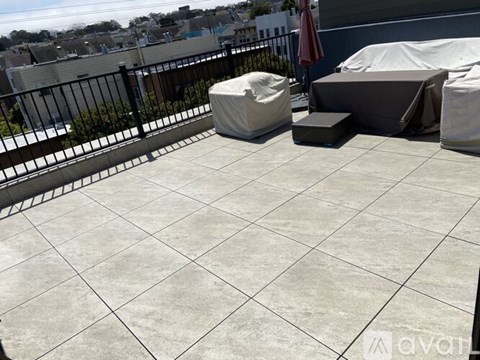 A patio with a black railing and a white couch.
