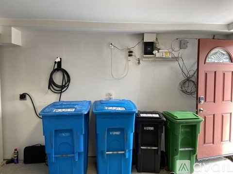 A wall with a hose and four bins.