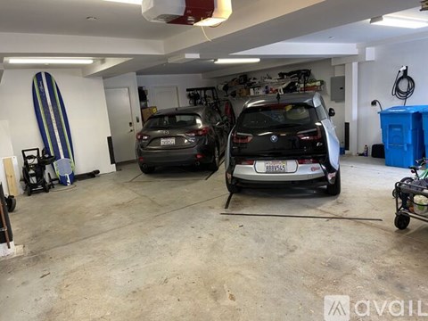 A garage with two cars and a surfboard.