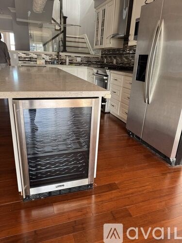 A kitchen with a stainless steel refrigerator and a wooden floor.