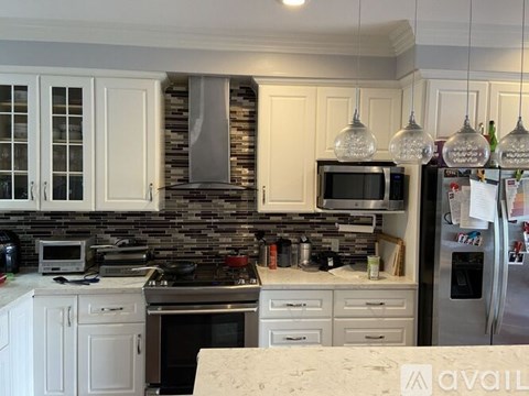 A kitchen with white cabinets and a stone backsplash.