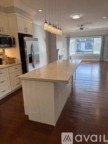 A kitchen with a white island and a black refrigerator.
