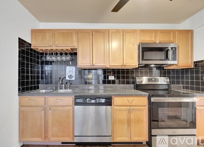 A kitchen with wooden cabinets and a black tile backsplash.