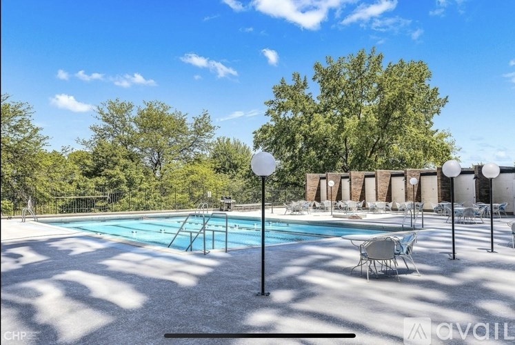 A pool surrounded by trees and chairs.