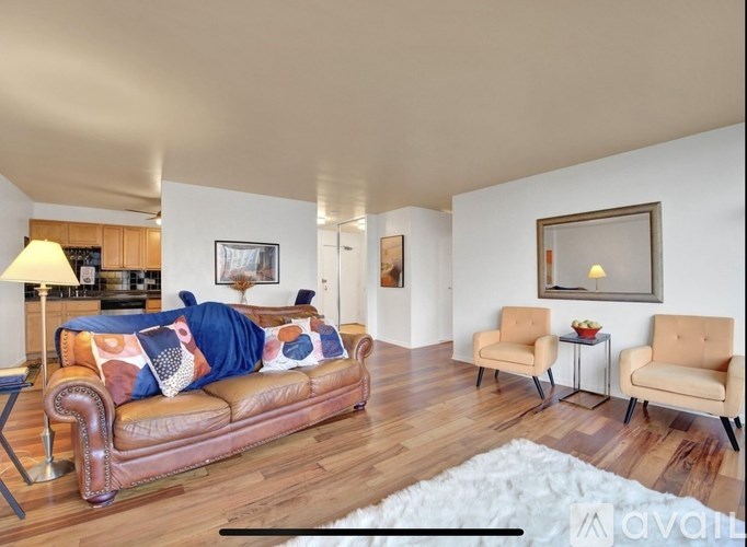 A living room with a brown leather couch and two beige armchairs.