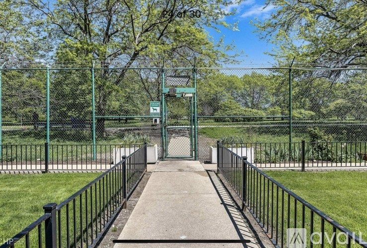 A green metal fence surrounds a walkway in a park.