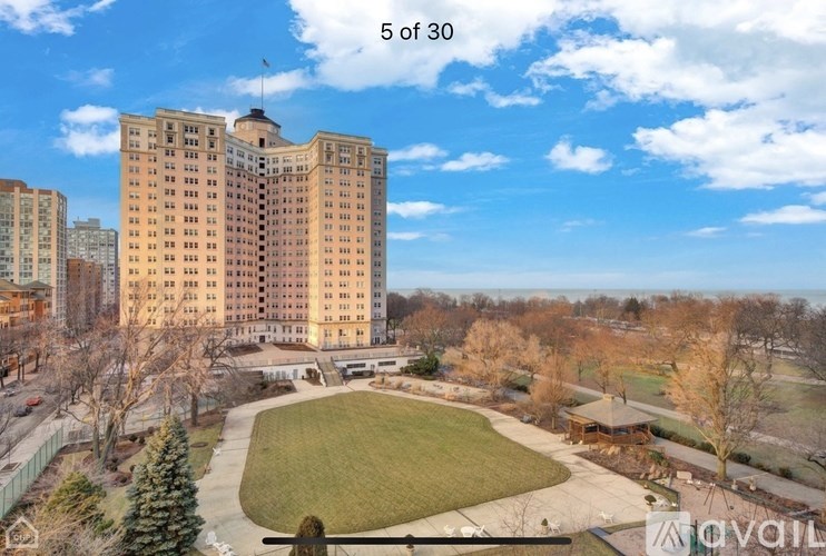 A large building with a flag on top is surrounded by a green lawn.