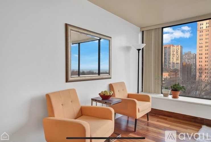 A living room with two chairs and a table with a bowl of fruit on it.