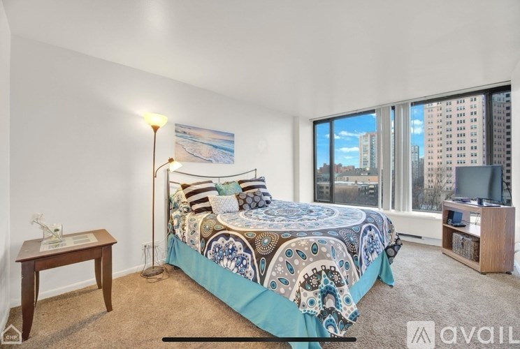 A bedroom with a large bed and a city view through the window.