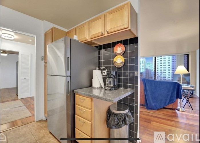 A kitchen with a refrigerator, a coffee maker, and a countertop with a towel hanging on it.