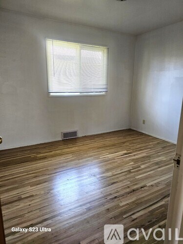 A room with wooden flooring and a window with blinds.