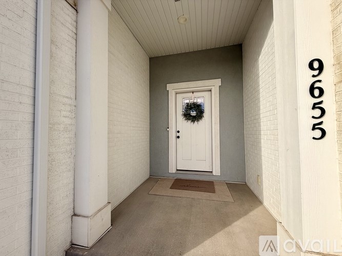 A white door with a wreath on it is in a hallway with a number 9655 on the wall.