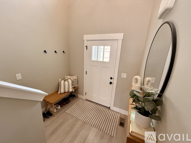 A bathroom with a white door, a round mirror, and a bench with towels on it.