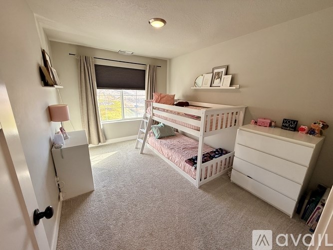 A white bunk bed with a single bed underneath it in a room with a window.