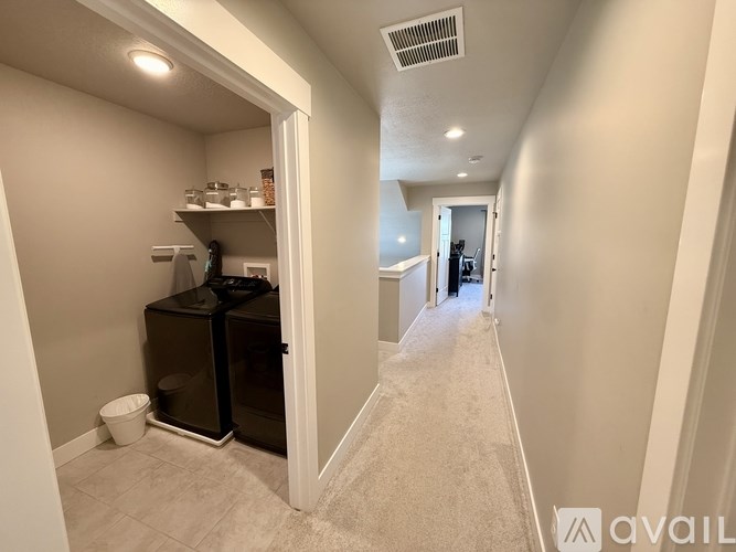 A hallway with a black refrigerator and a white door.