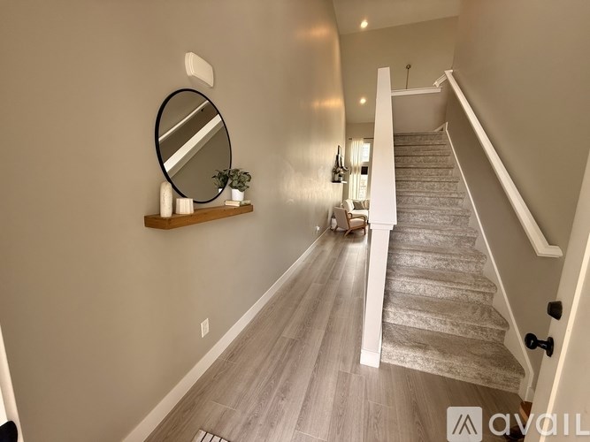 A hallway with a staircase and a mirror on the wall.