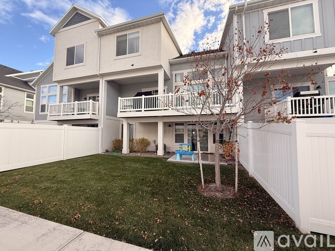 A large two-story house with a white fence and a tree in front.
