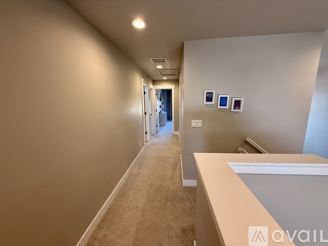 A hallway with beige walls and carpeting, leading to a door at the end.