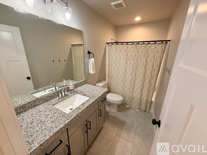 A bathroom with granite countertops, a sink, toilet, and shower.