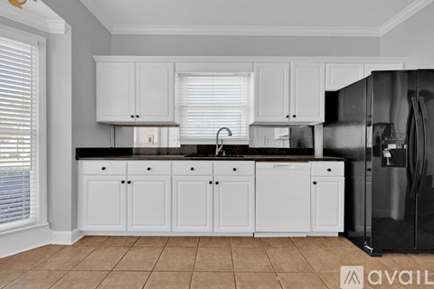 A kitchen with white cabinets and a black fridge.